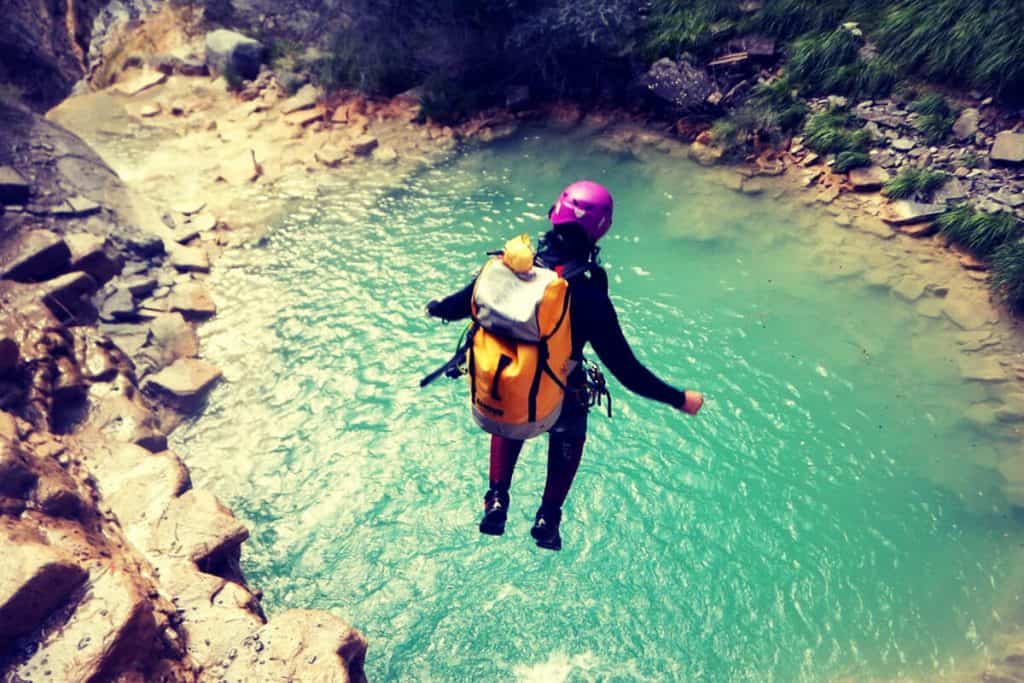 persona haciendo barranquismo y tirandose de un rio