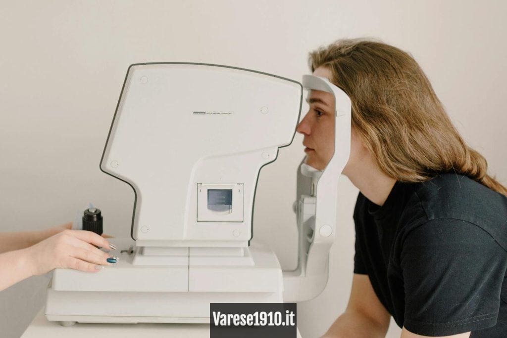 Side view of crop anonymous doctor checking eyesight of female patient using vision screening device in clinic